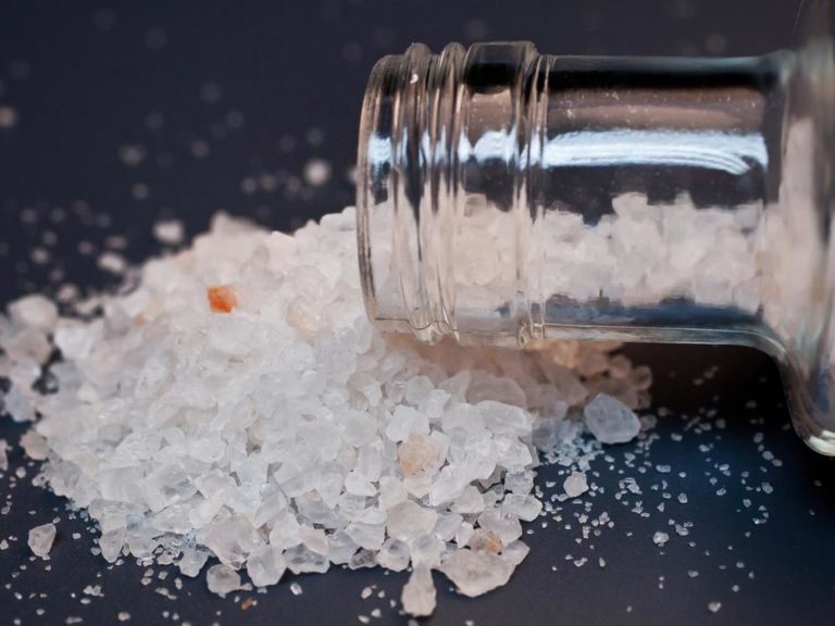 glass bottle containing bath salts spills on table