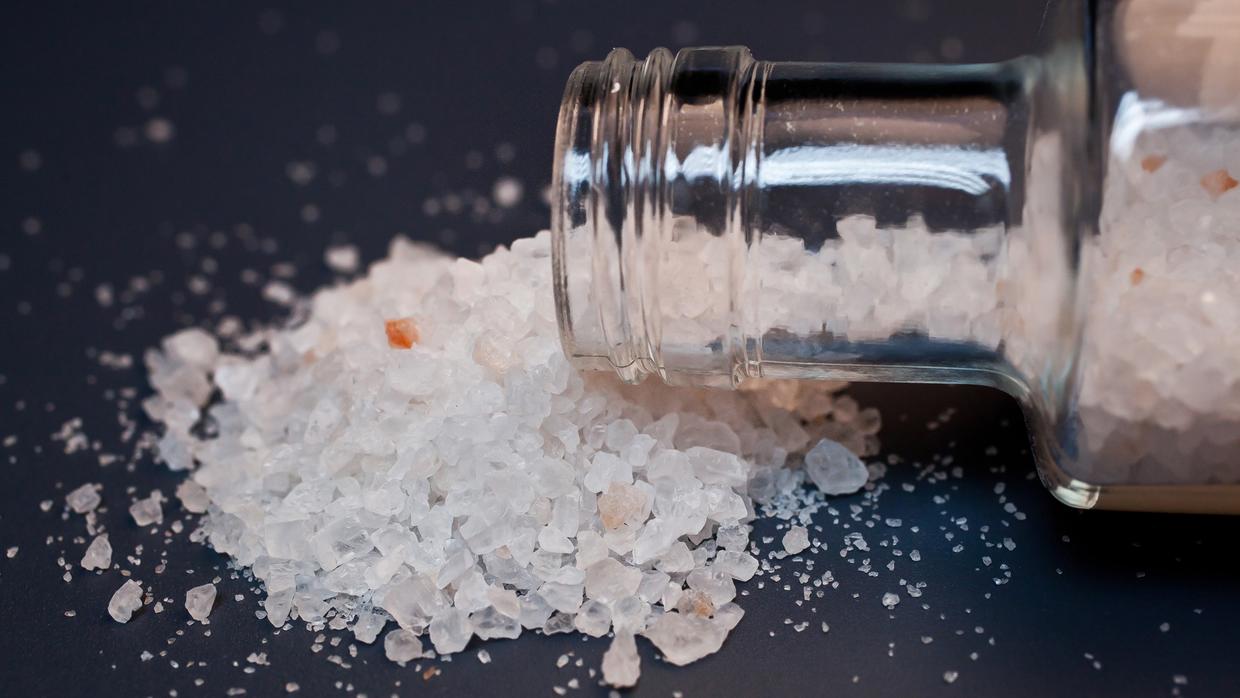 glass bottle containing bath salts spills on table