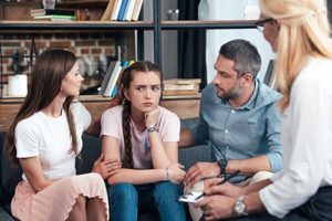 a counselor sits with a mom, dad and teen girl in a Teen Family Therapy