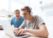 Teen wearing headphones playing on computer and ignoring father