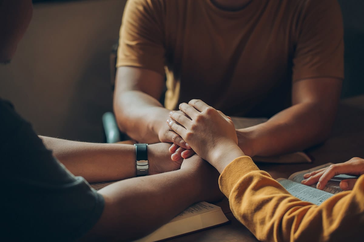 person in yellow shirt comforting another and helping them with coping with grief and loss