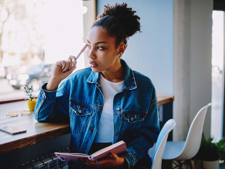 woman sitting by window considers what is double discrimination