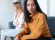 person in yellow sweater looks away from other person on couch while discussing compulsive reassurance seeking