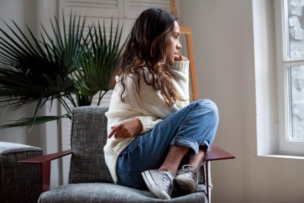 girl curls up on chair and considers anticipatory anxiety