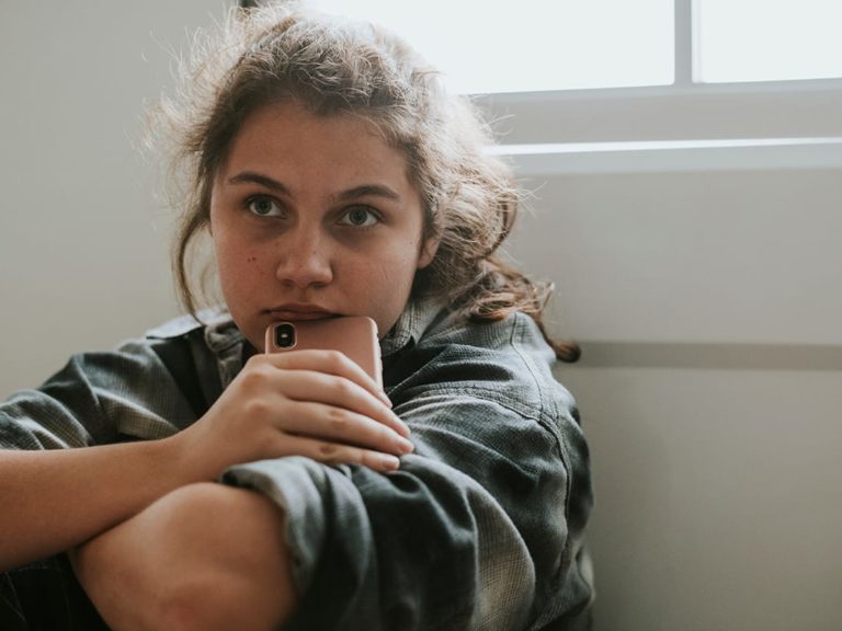 girl sitting by window considers puberty and mental health