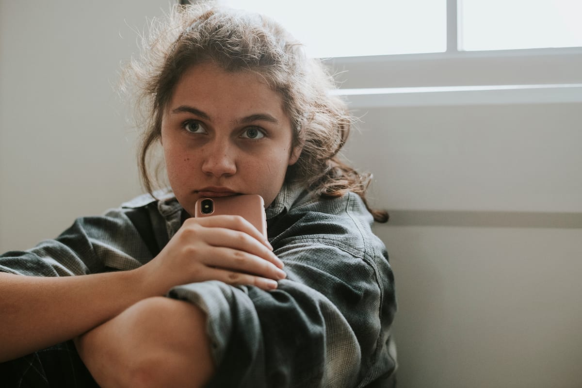 girl sitting by window considers puberty and mental health