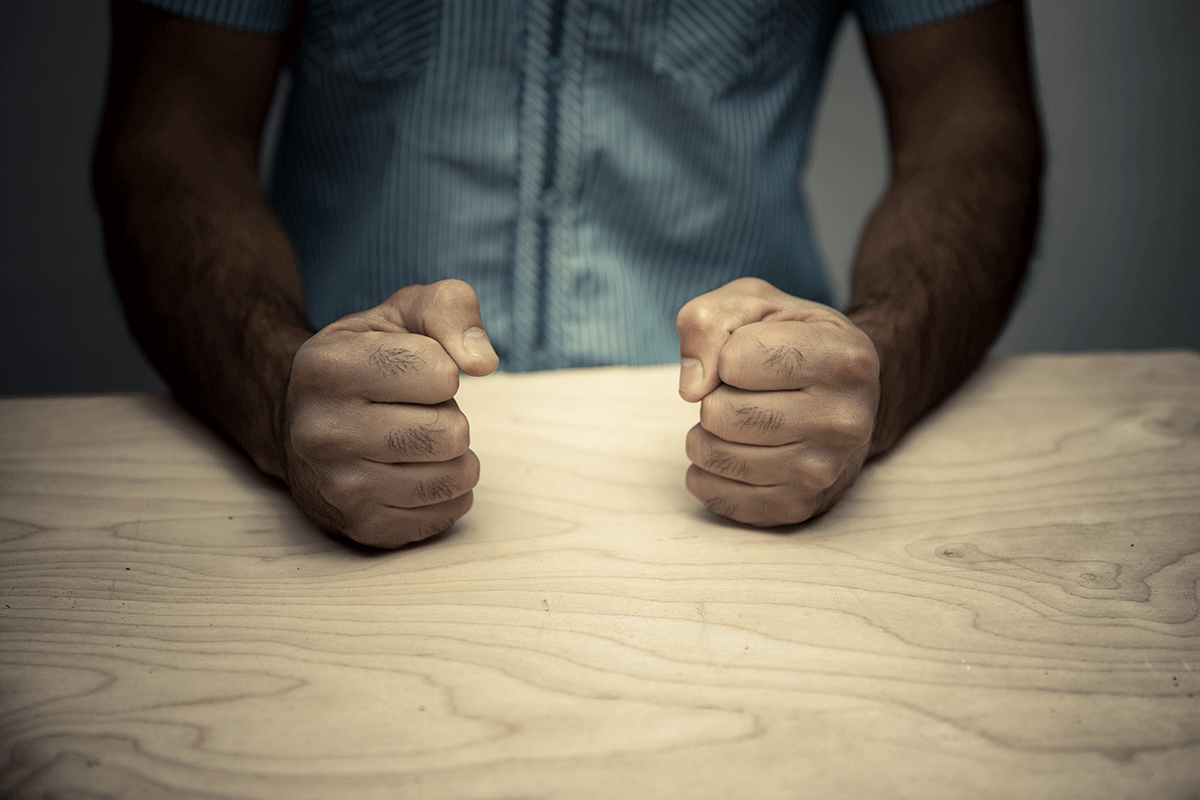 person puts fists on table while learning about anger cues