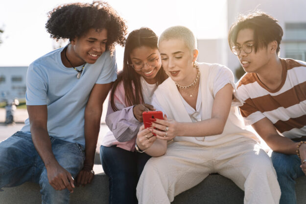 teens looking at a phone outside with social confidence