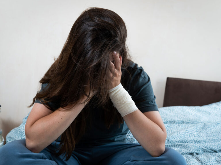 teen sitting on bed thinking about their self-harm motivations