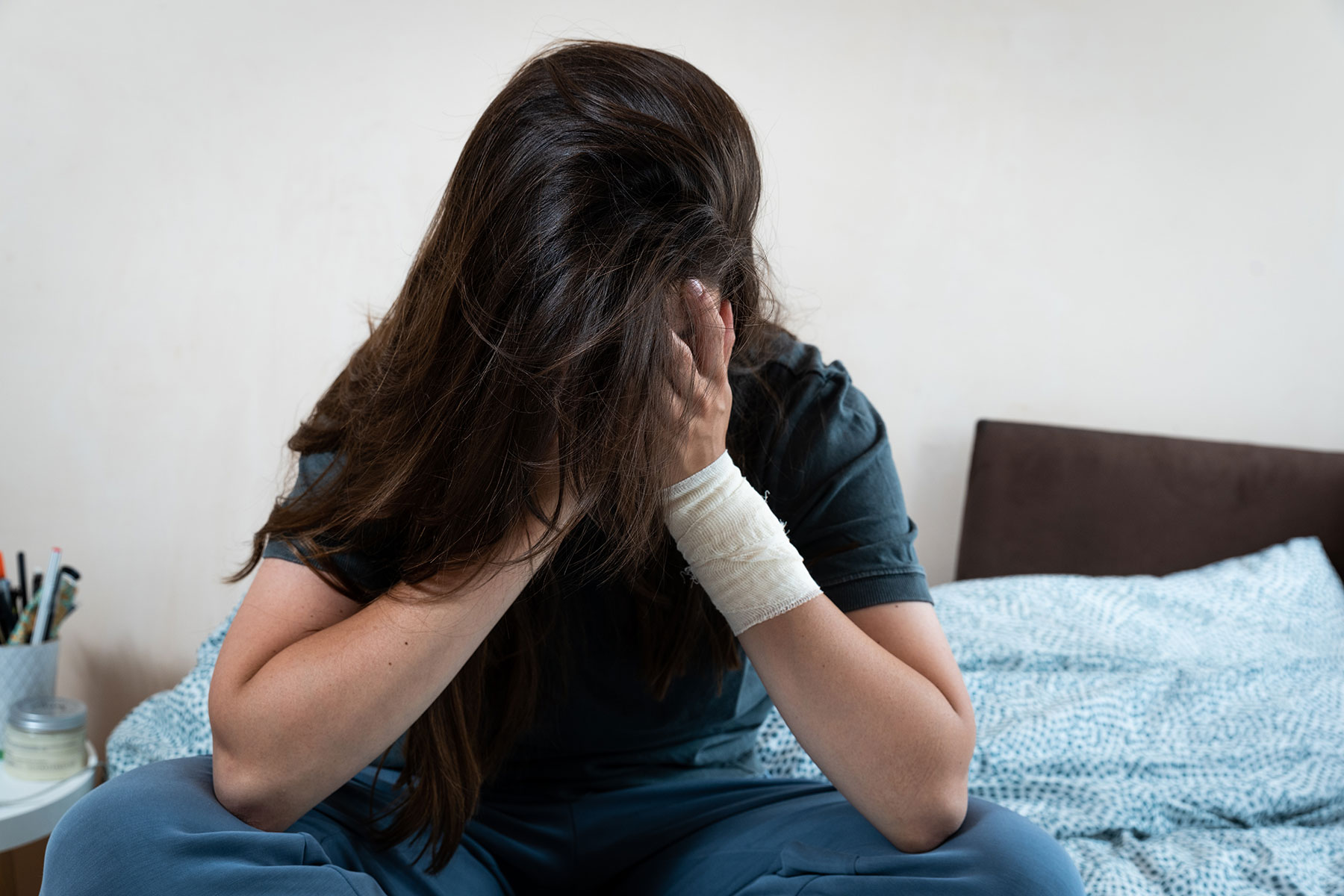 teen sitting on bed thinking about their self-harm motivations