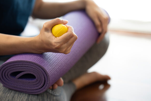 person holds stress ball on top of a yoga mat while learning how to channel anger