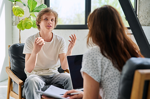 teen talks with therapist about self-harm and cutting behaviors