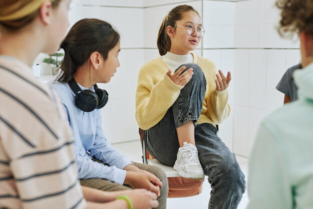 teen in yellow sweater talks with group about the origin of BIPOC mental health month