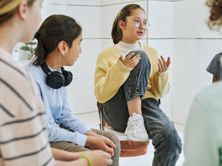 teen in yellow sweater talks with group about the origin of BIPOC mental health month
