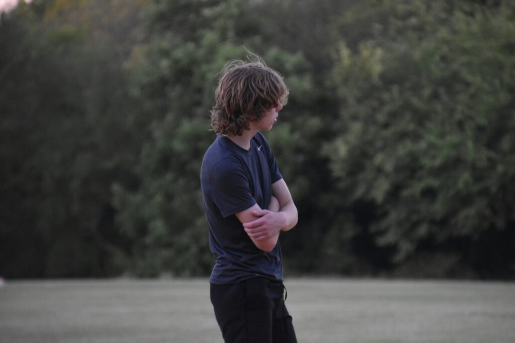 teen boy standing alone looking depressed