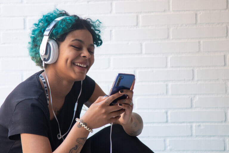 portrait of young woman with mobile phone and headphones listening to music