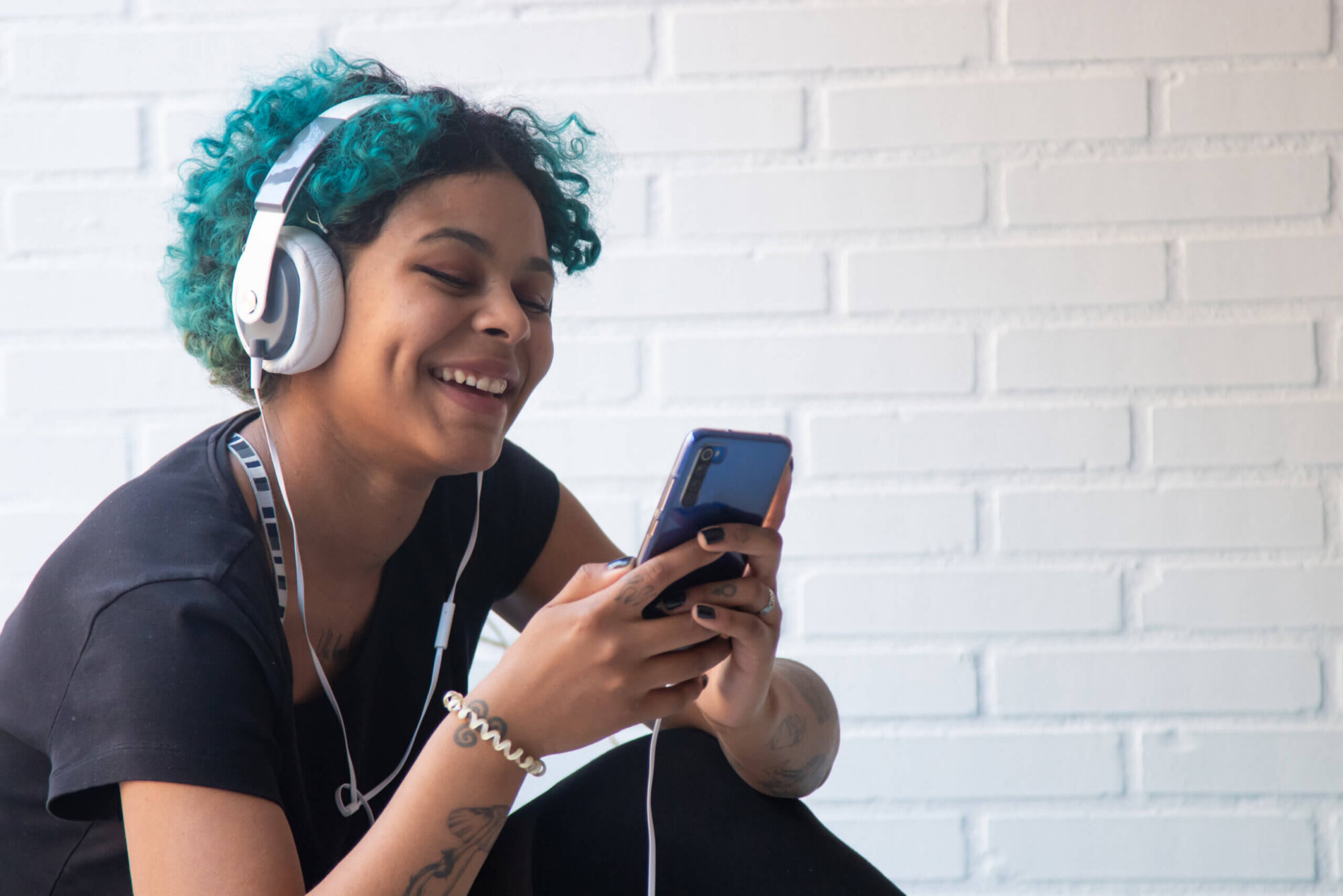 portrait of young woman with mobile phone and headphones listening to music