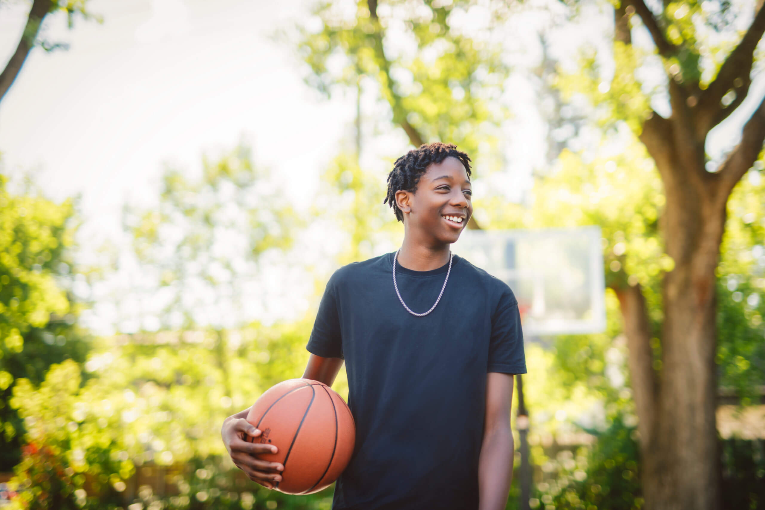 portrait of a teen playing with a basketball in park