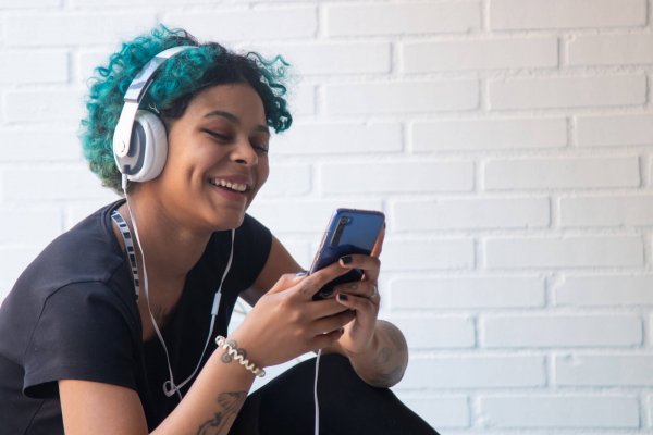 portrait of young woman with mobile phone and headphones listening to music